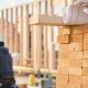 Pile of lumber stacked in the foreground in a photo of a construction site